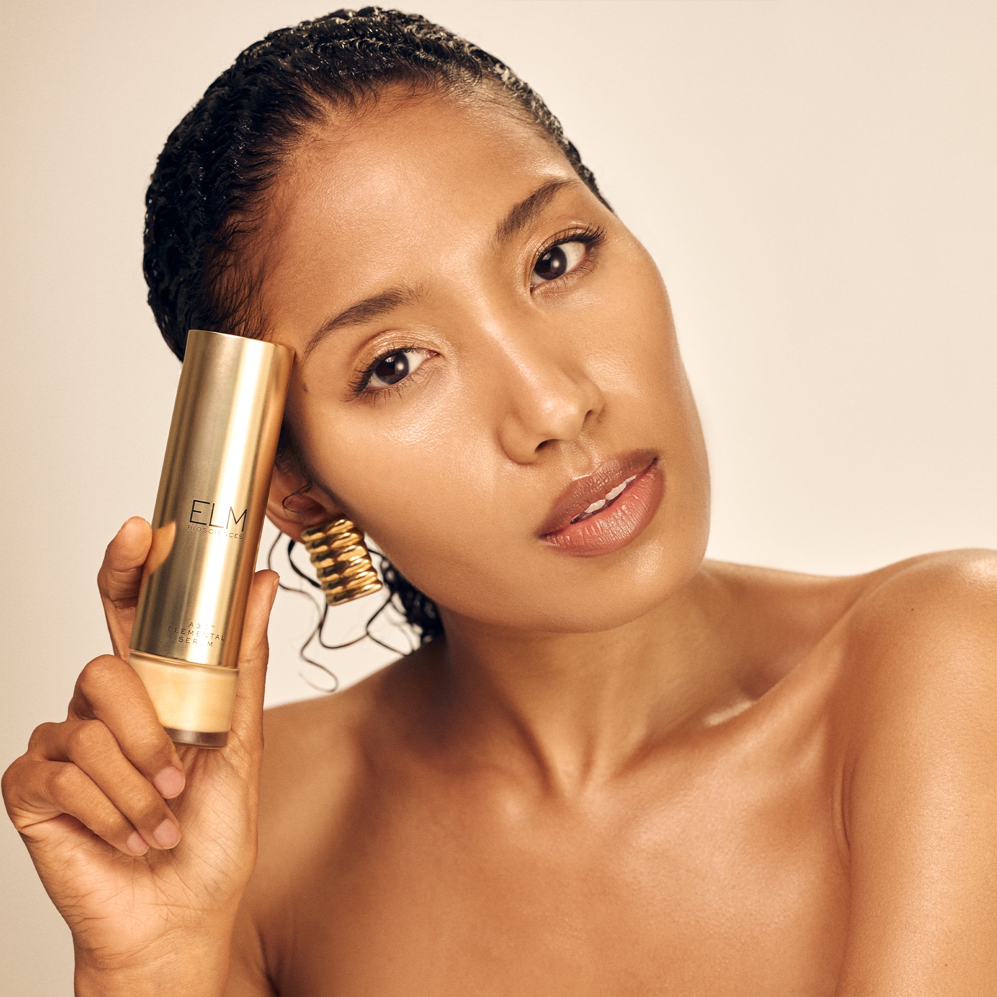 Woman holding a A3O™ Elemental Serum bottle with a neutral background