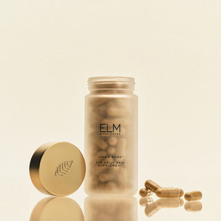 ELM Biosciences skincare product with gold cap and capsules on a beige background